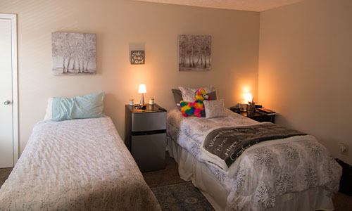 Two twin beds in a bedroom at The 4th Dimension women's sober living facility