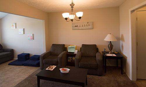 a shared living space with two chairs and two tables in a sober living home