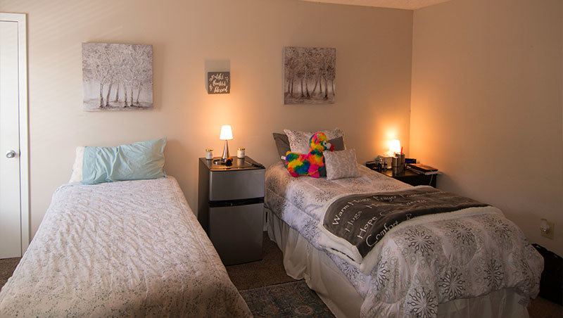 Women's sober living bedroom with two twin beds and a mini fridge