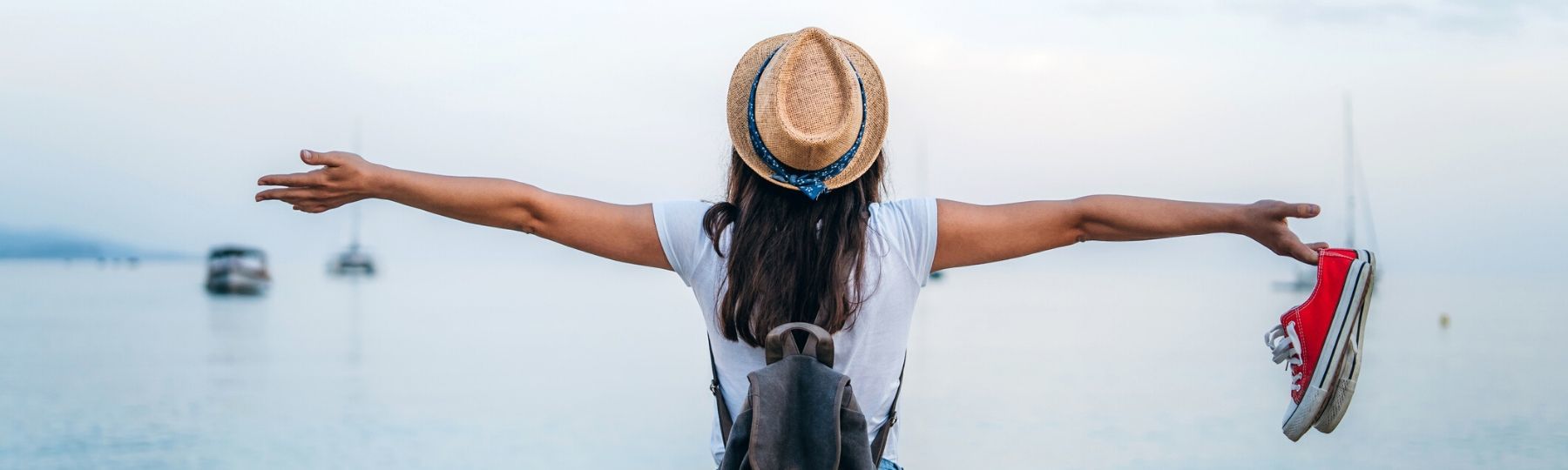 a women facing the sea with her arms open